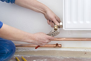 A plumber that has taken on self-employment fixing a radiator
